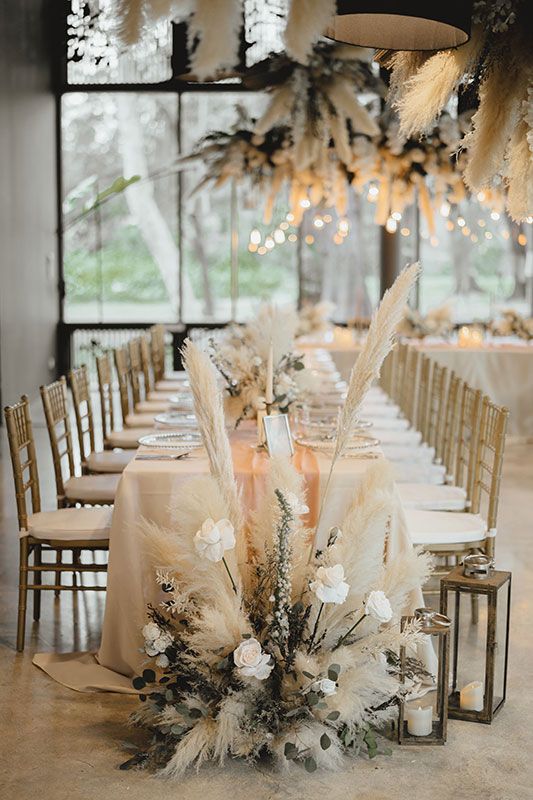 a long table with white flowers and feathers is set up for an elegant wedding reception