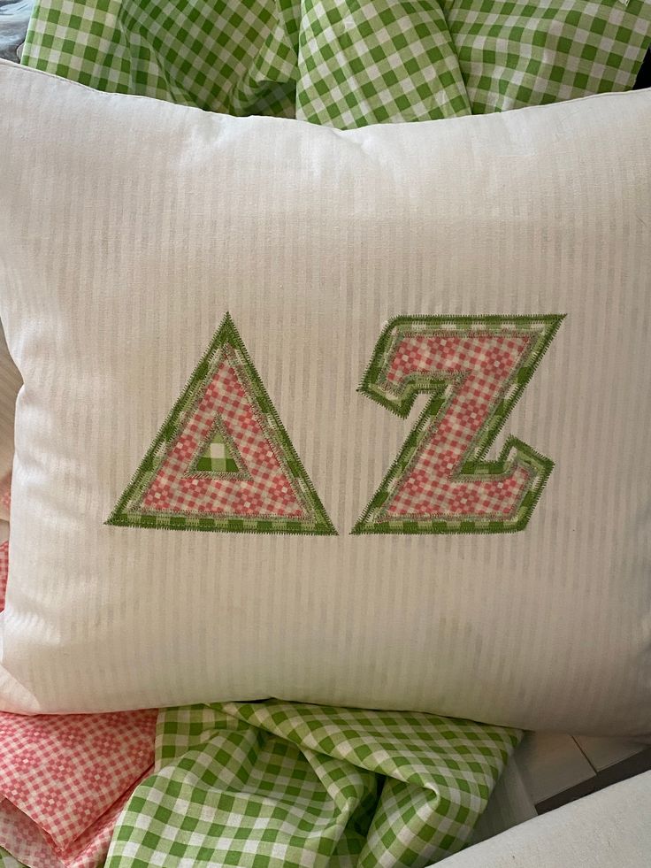 a white pillow with green and pink gingham checkered pillows on top of it