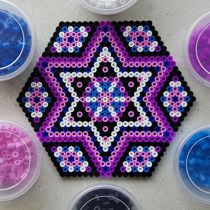 several different colored beads in plastic containers on a table with one bead and the other beaded