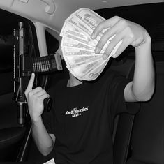 a man sitting in the back seat of a car drinking from a plastic bottle with money on it