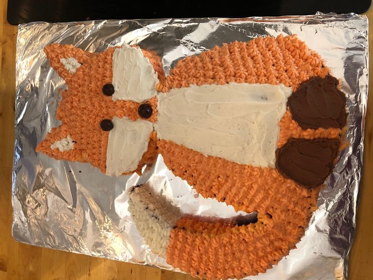 a cake made to look like a fox on tin foil with brown and white frosting