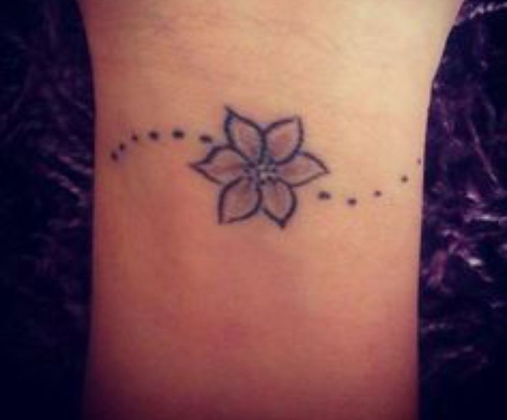 a small flower tattoo on the ankle with dots around it and stars at the bottom