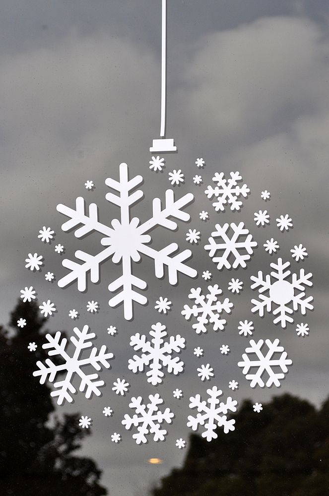 a snowflake hanging from the side of a window with trees in the background