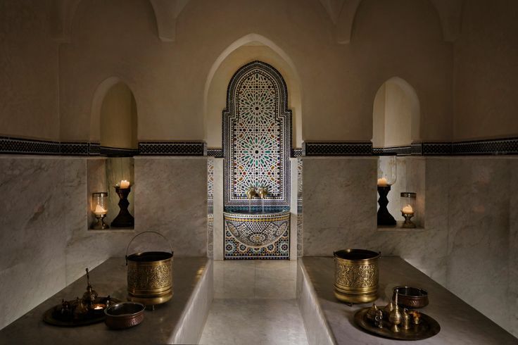 the interior of a bathroom with two sinks and candles on the wall, in front of an arched doorway