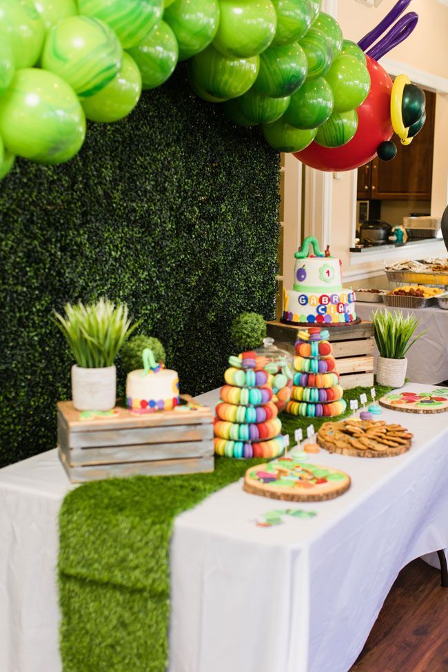 a table topped with lots of green balloons and desserts on top of white tables