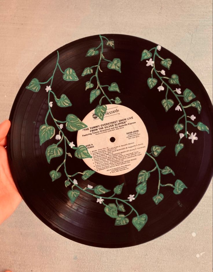 a hand holding a record with green leaves on it