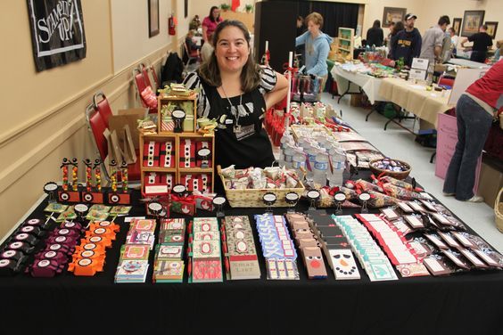 a woman standing in front of a table filled with lots of different types of items