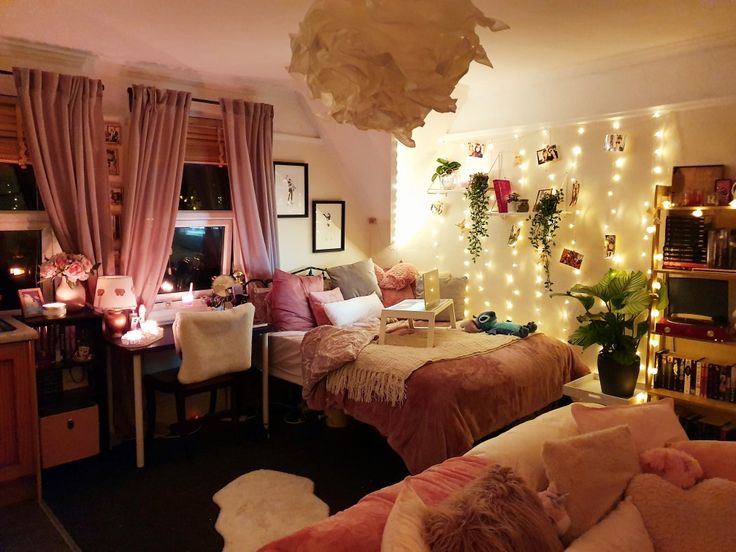 a bedroom with lights strung from the ceiling and pink curtains on the window sill