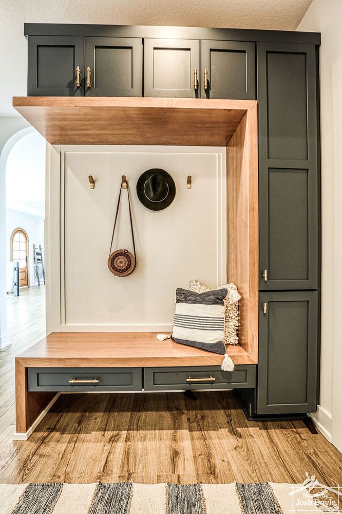 an entryway with a bench, coat rack and hat on the wall above it