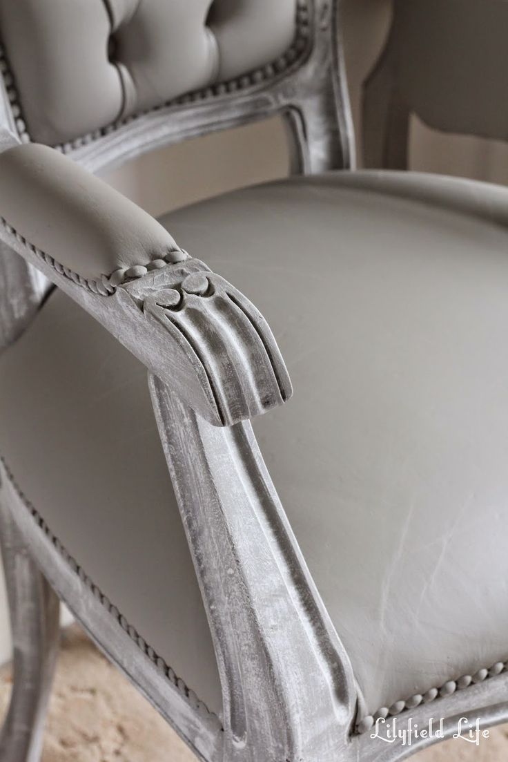 an upholstered chair with white leather and silver trim on the armrests