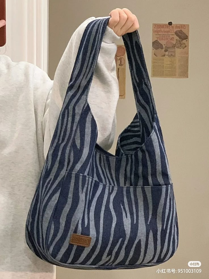 a woman holding up a blue and white zebra print handbag in front of her face