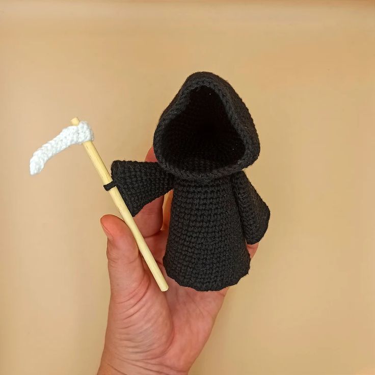 a crocheted figure holding a toothbrush in it's mouth and wearing a black robe