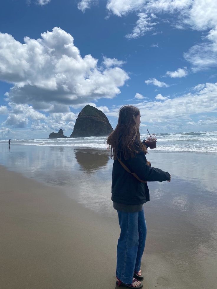 a woman standing on top of a beach next to the ocean