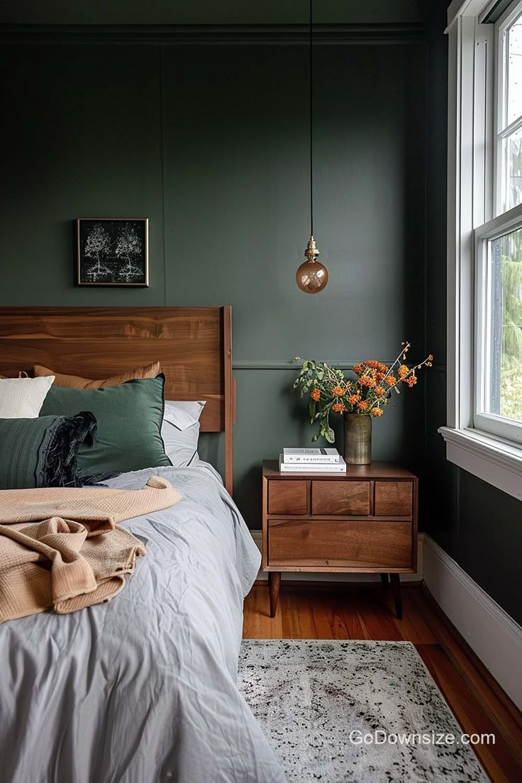 a bedroom with dark green walls and white bedding, wooden headboard and nightstand