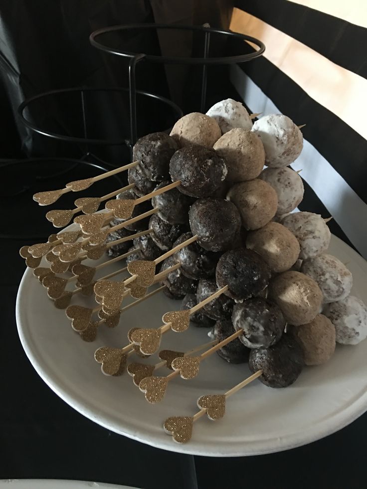 a white plate topped with chocolate covered donuts and lollipops on sticks