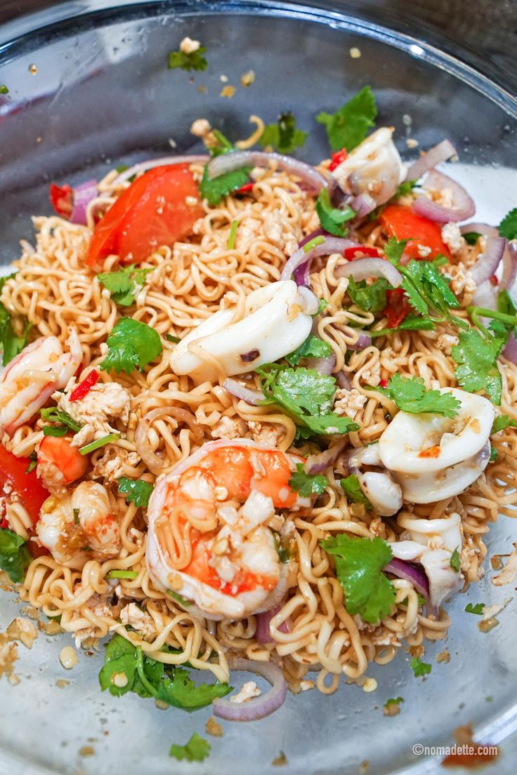 a close up of a plate of food with noodles and shrimp on it, garnished with cilantro