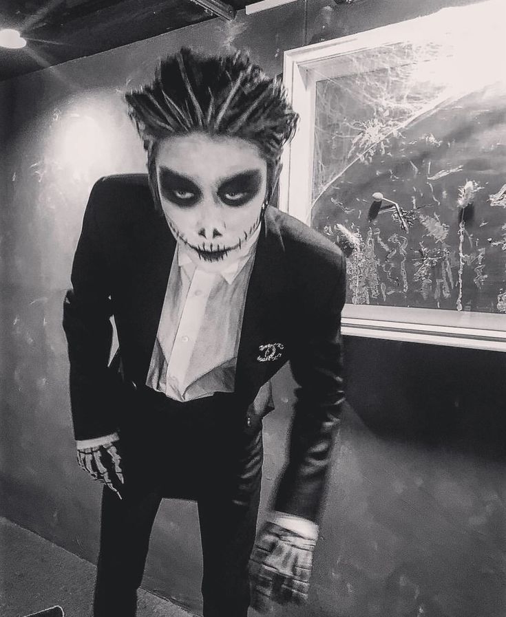 a man dressed up as the joker in a black suit and tie with his hands on his hips