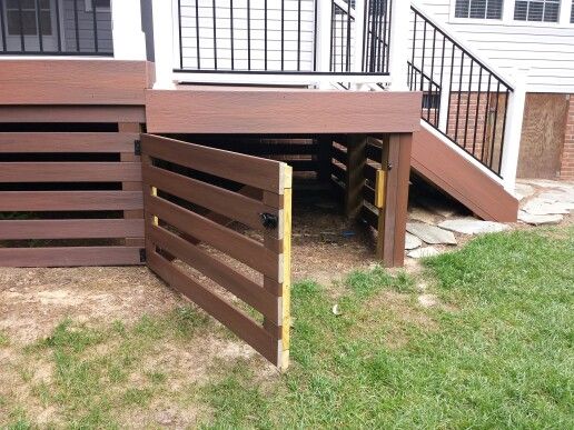 a wooden deck with stairs leading up to the top floor and below it is an open door