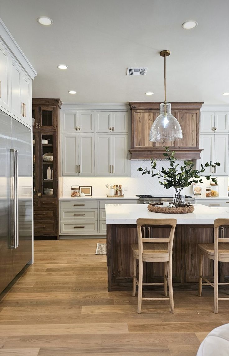 a large kitchen with wooden floors and white cabinetry, along with an island in the middle