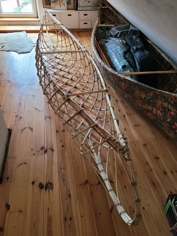 a wooden boat sitting on top of a hard wood floor next to an open window