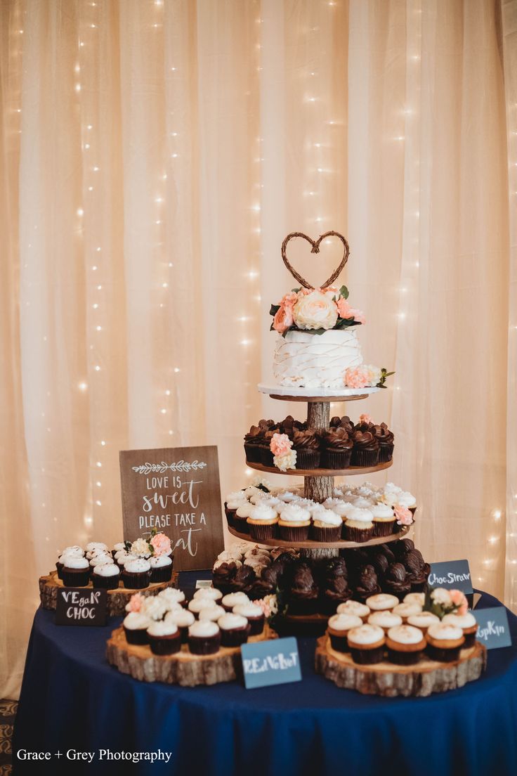 a table topped with three tiered cakes and cupcakes