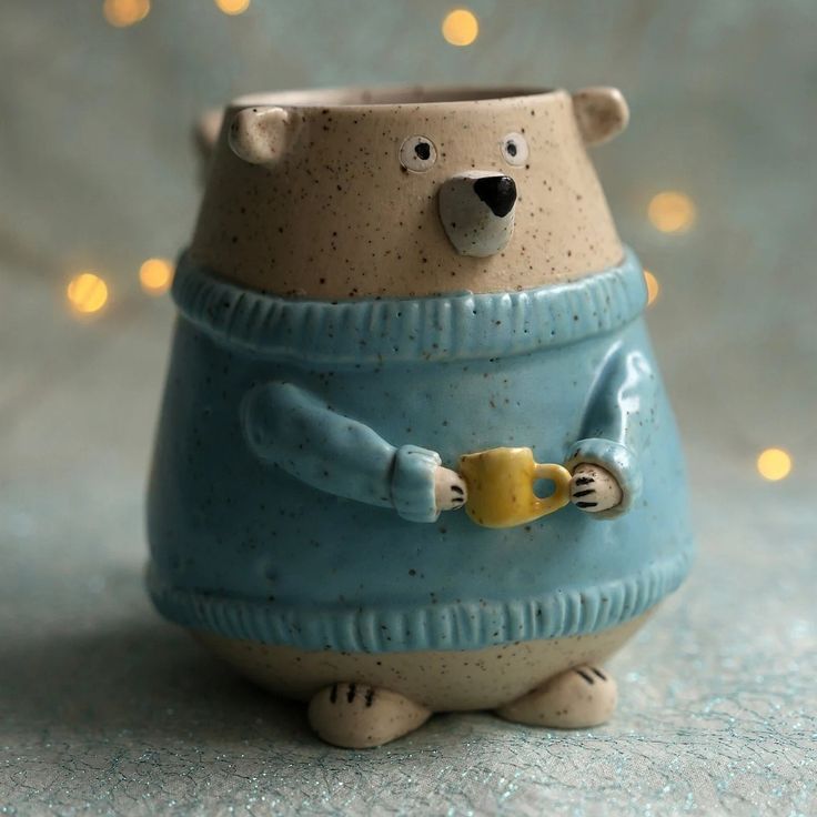 a ceramic bear with a sweater on holding a cup