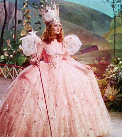 an old photo of a woman in a pink dress and tiara holding a cane