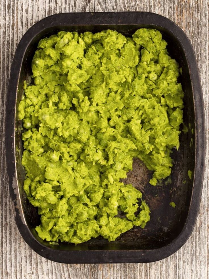 a pan filled with green food on top of a wooden table