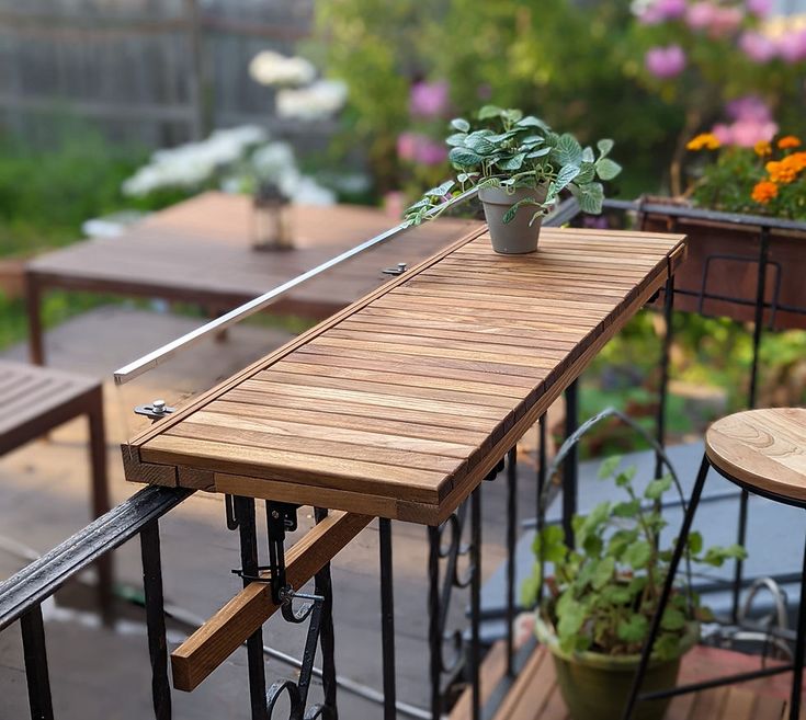 a wooden table sitting on top of a balcony next to potted plants and chairs