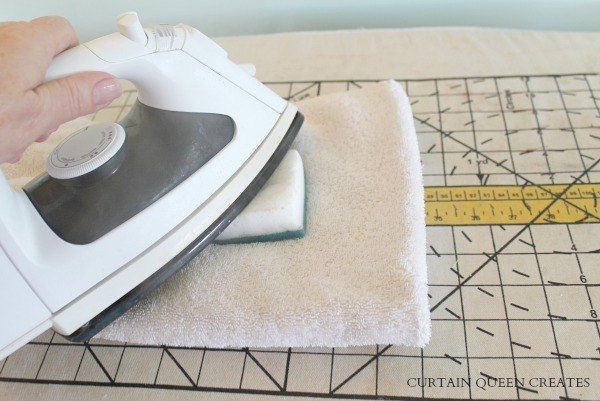 a person ironing fabric on top of a cutting board with a white and black iron