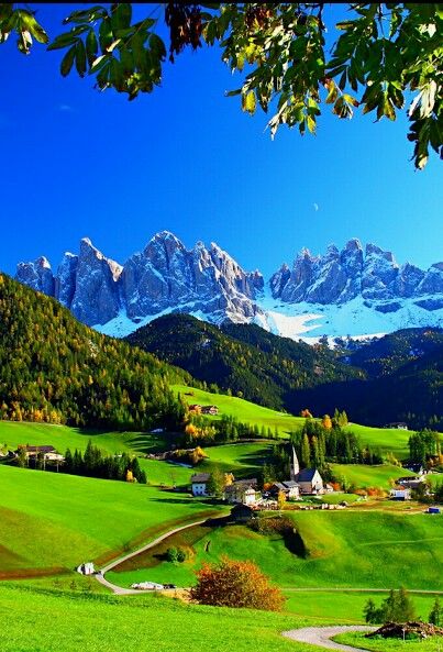 the mountains are covered in snow and green grass, with small houses on each side