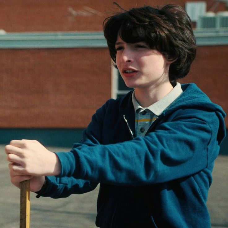 a young boy holding a baseball bat on the street