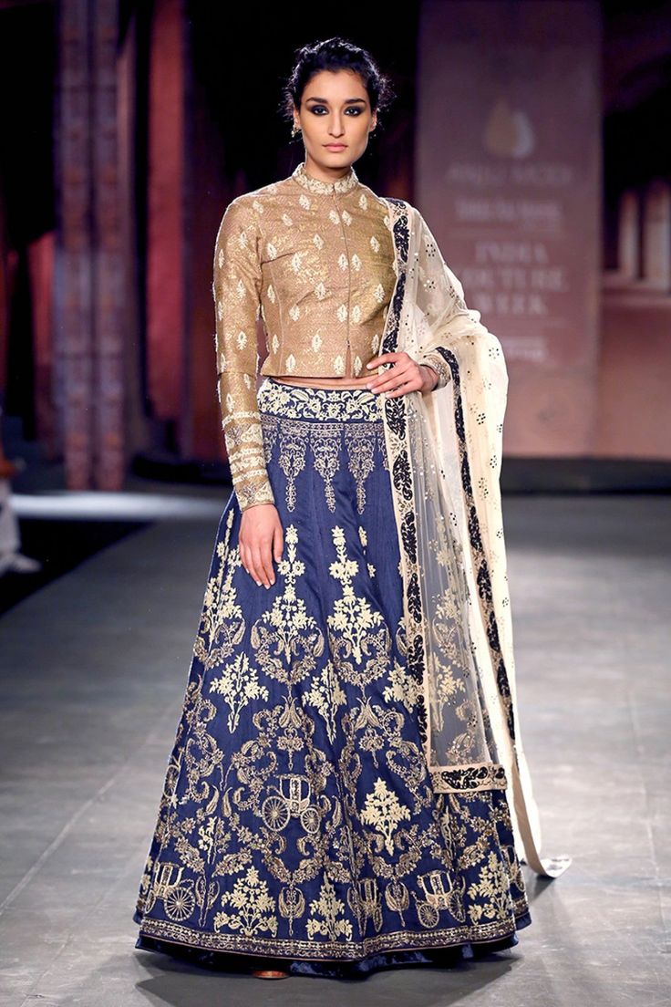 This lehenga is embroidered in zari and dabka in raw silk lehenga along with a golden blouse. Blouse is also has hand-embellished detailing on neck and sleeves. A mokaish net dupatta with a floral patterned border completes the look of this lehenga. Long Choli Blouse Design, Indigo Lehenga, Homemade Bars, Choli Blouse Design, Golden Blouse, Long Blouse Designs, Lehenga Pattern, Raw Silk Lehenga, Indian Lehenga Choli