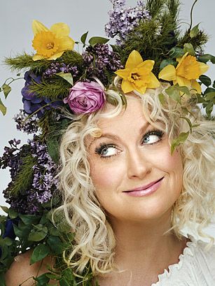 a woman with blonde hair and flowers in her hair is smiling at the camera while wearing a flower crown