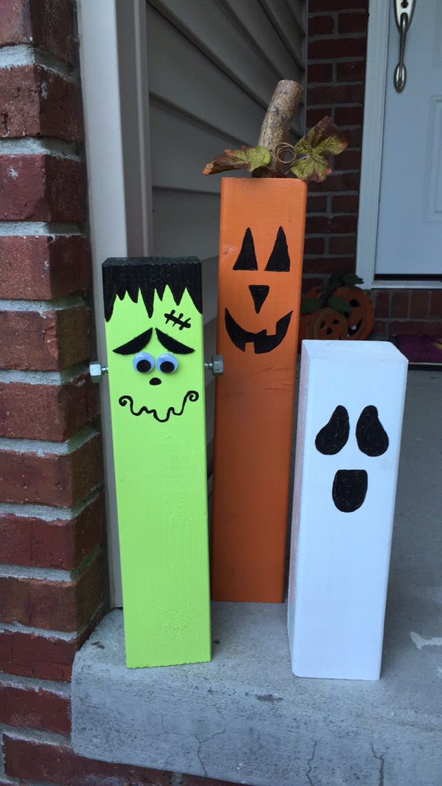 three halloween decorations are sitting on the front porch, one painted green and one decorated orange