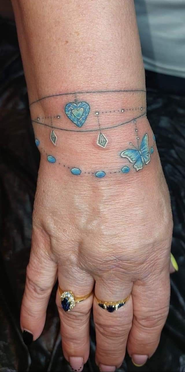 a woman's hand with tattoos on it and two butterflies attached to the wrist