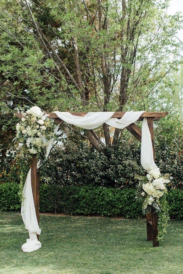 an outdoor ceremony setup with white flowers and greenery