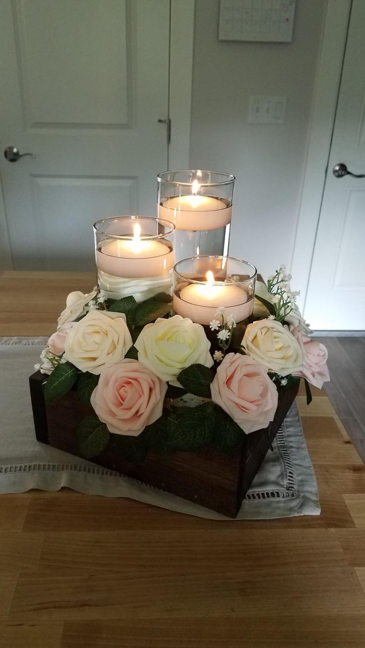 candles are placed on top of a wooden box with flowers and greenery in it