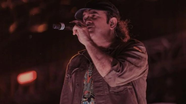 a man standing on top of a stage holding a microphone in his hand and looking up