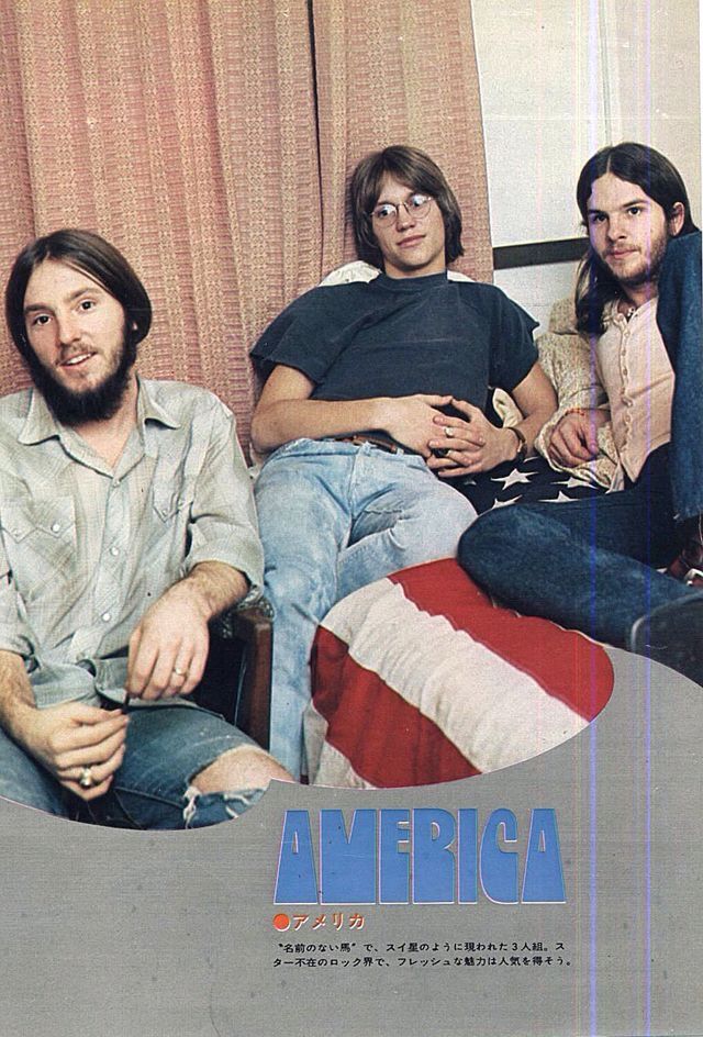 three men sitting on a couch in front of an american flag