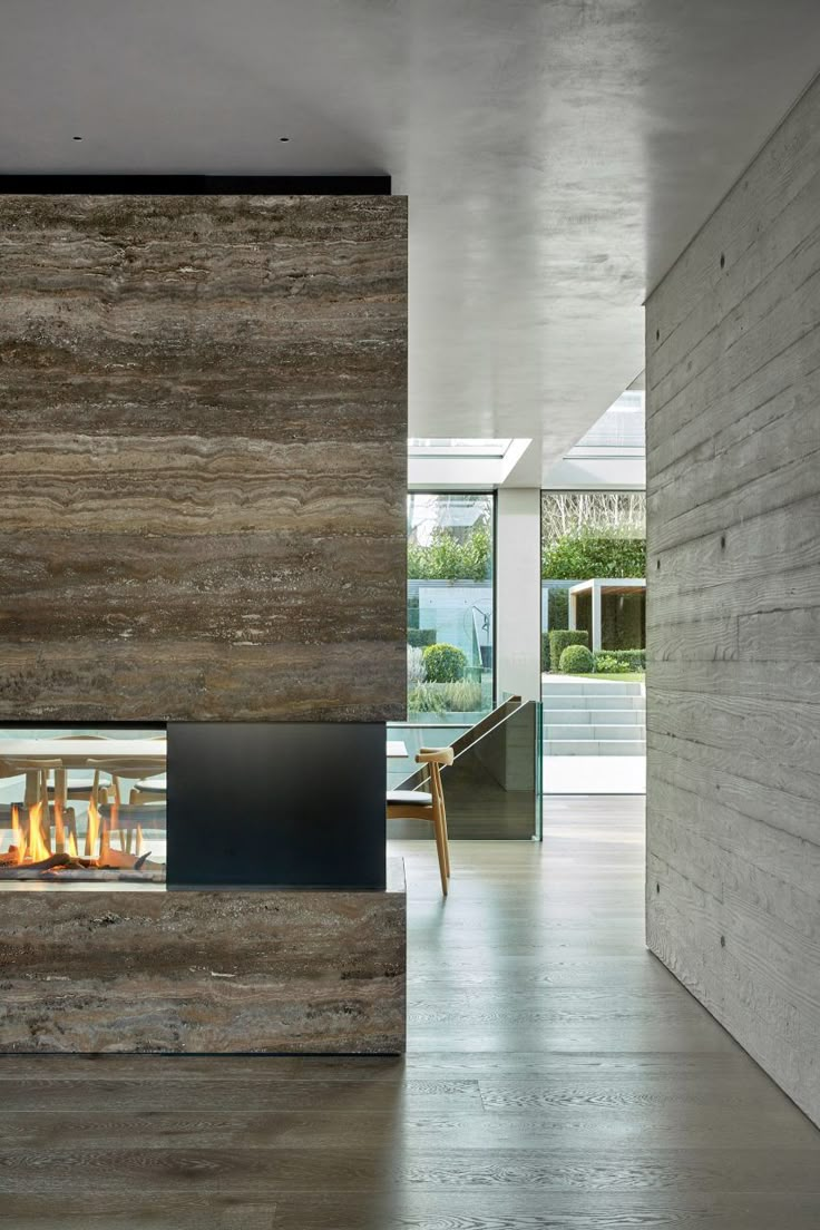 a modern fireplace in the middle of a room with wood paneling and glass doors