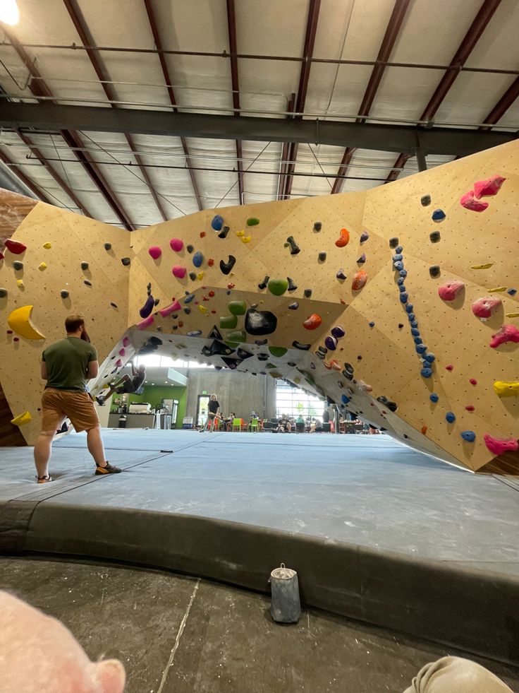 two people climbing up the side of a rock wall in an indoor climbing gym,