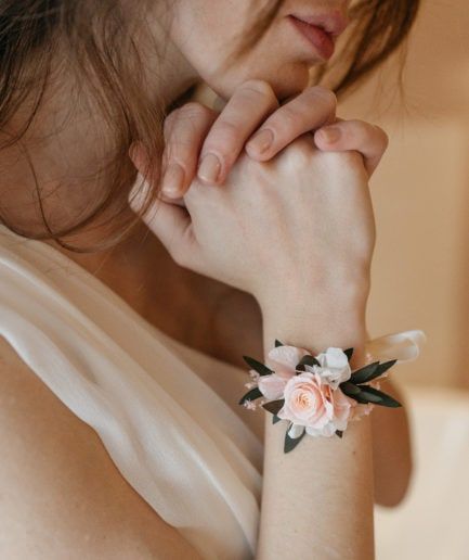 a woman wearing a bracelet with flowers on it's wrist and holding her hand near her face