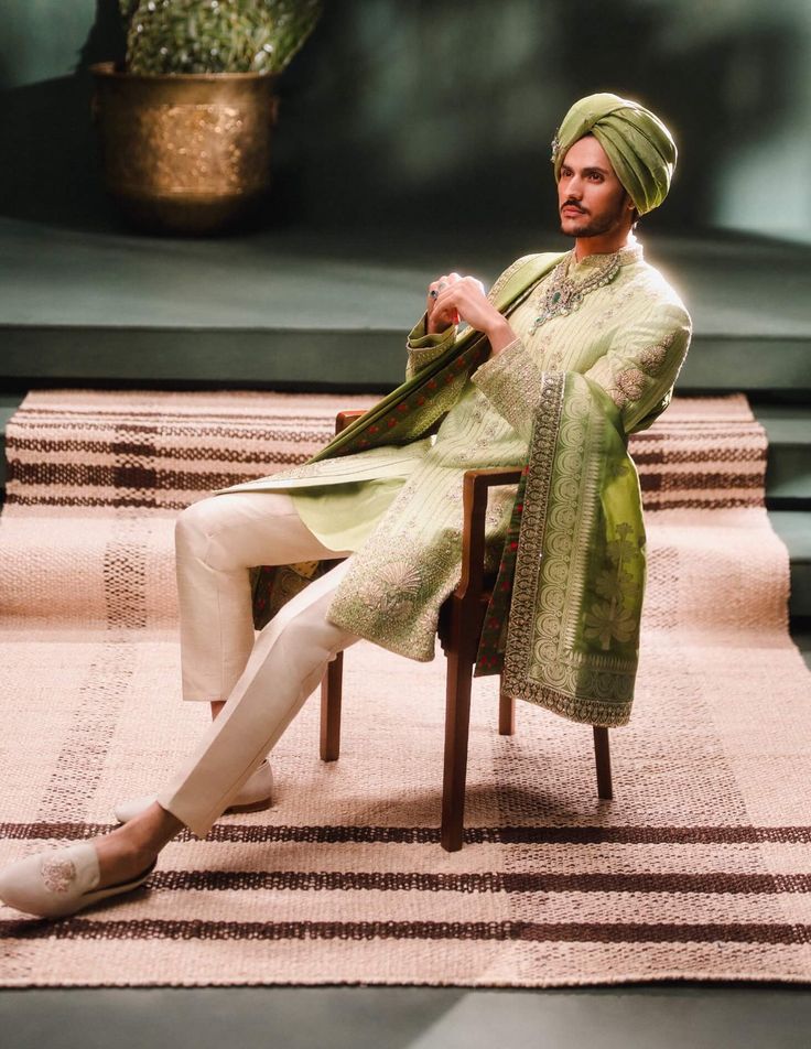 a man sitting in a chair wearing a green turban