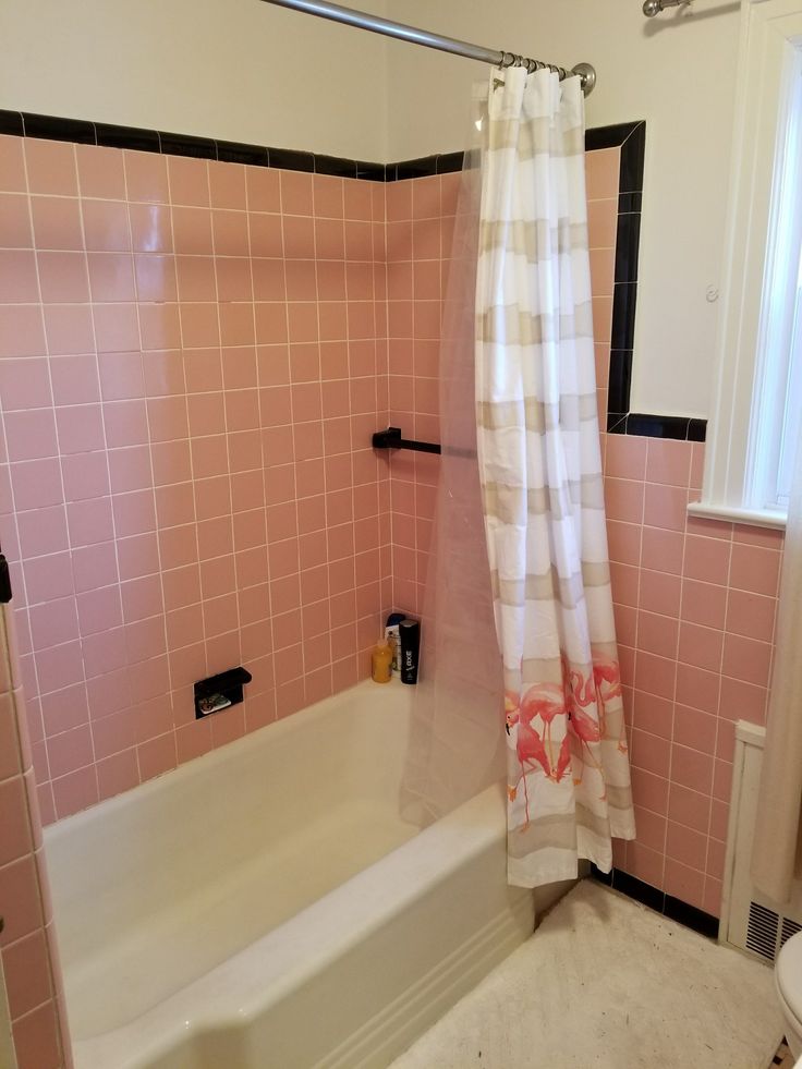 a bathroom with pink tiles on the walls and bathtub, shower curtain, and toilet