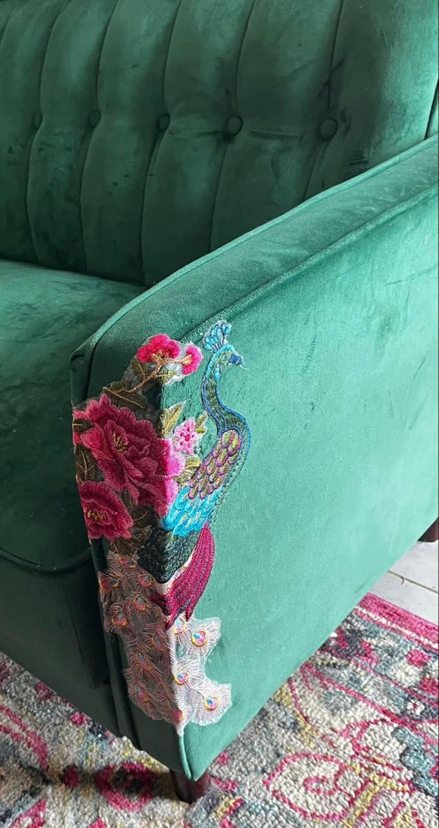 an upholstered green velvet couch with colorful embroidered details