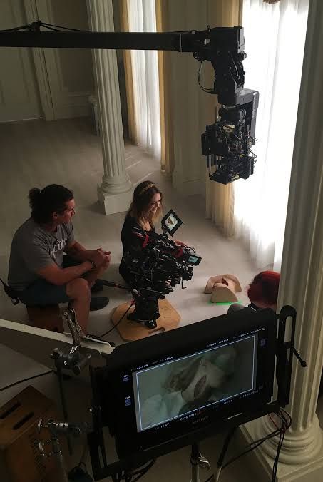 two people sitting on the ground in front of a camera set up for a video