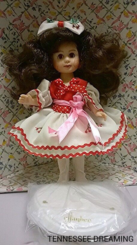 the doll is wearing a red and white dress