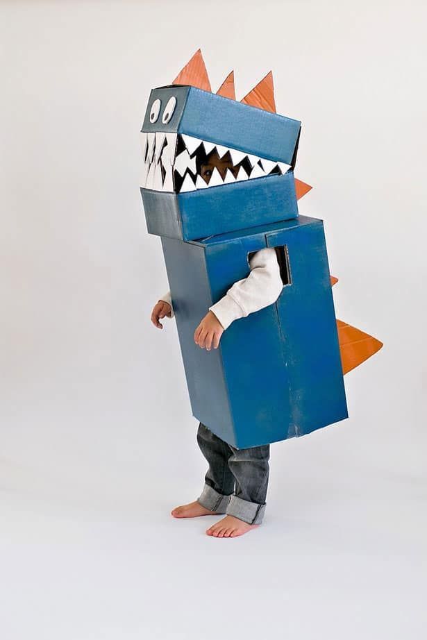 a young boy dressed up as a shark with his mouth open and teeth out, standing in front of a white background