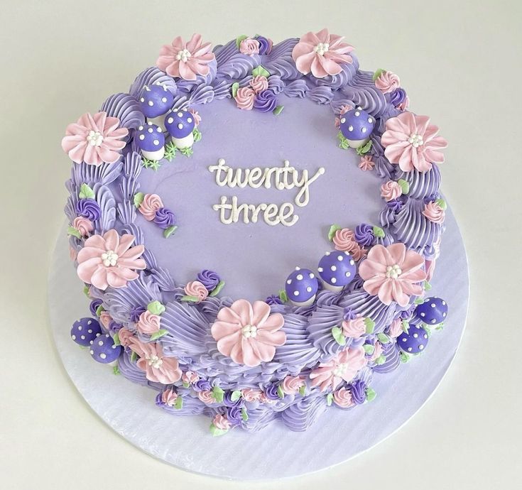 there is a purple cake decorated with flowers and the words twenty three on it's side